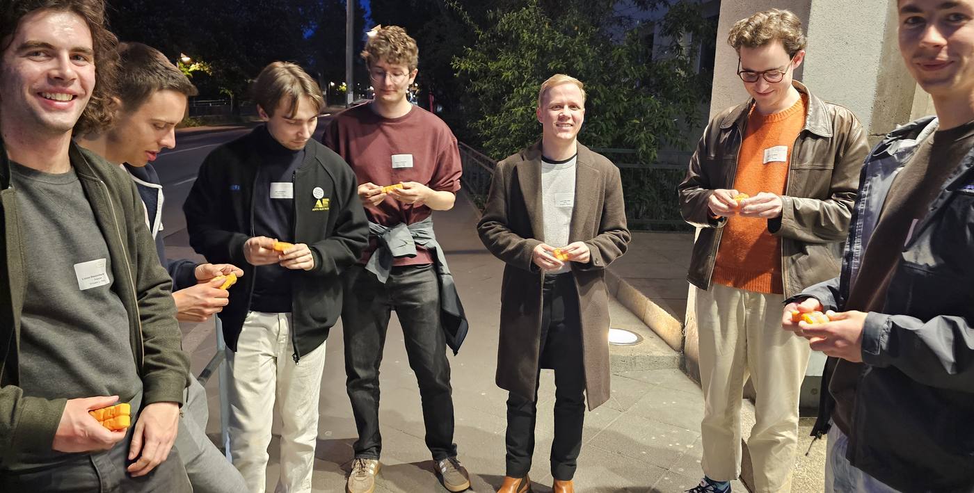 Gruppe junger Leute abends draußen, alle spielen mit ihren orangenen CUBYs