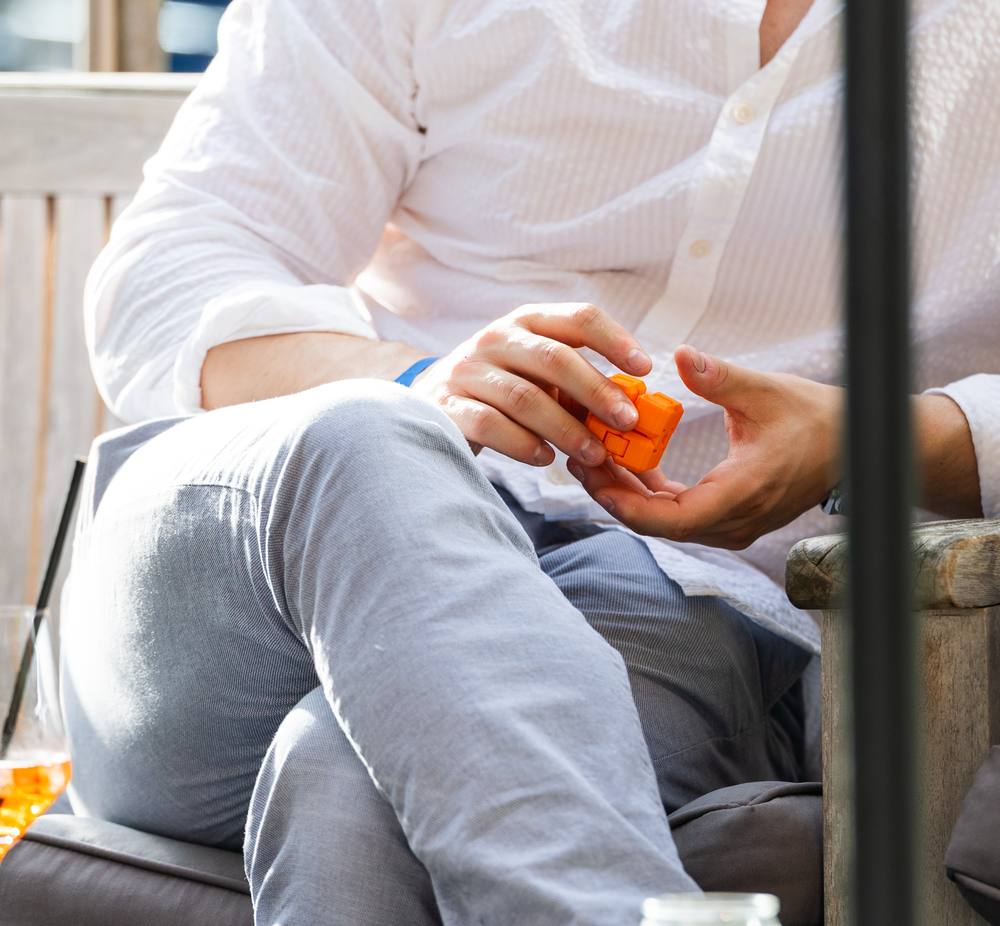Mann hält beim Afterwork entspannt einen orangenen CUBY in der Hand
