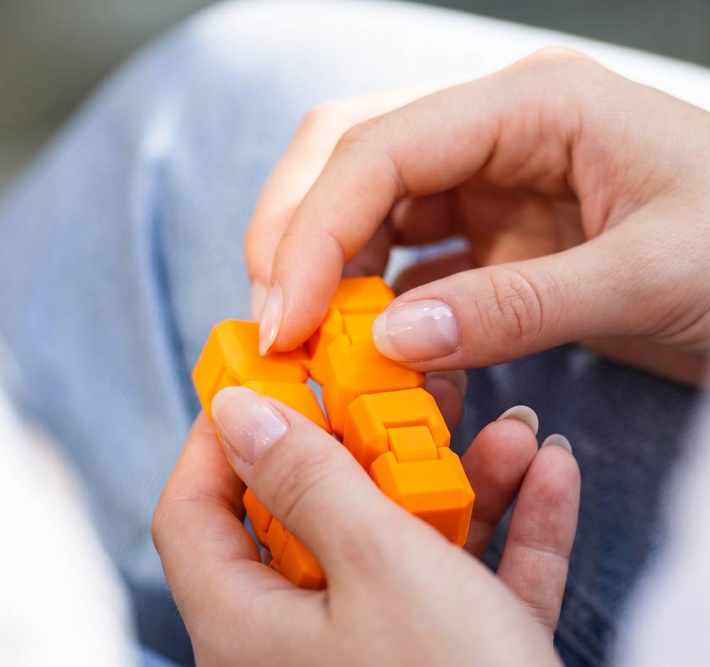 Manikürte Hände einer Frau, die einen orangenen CUBY drehen