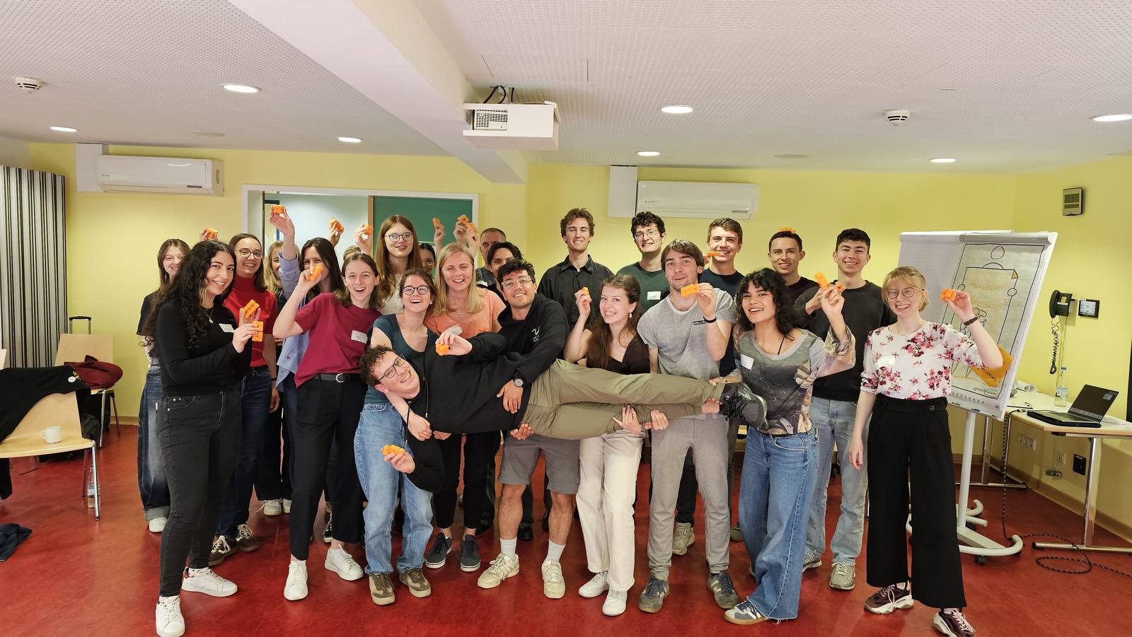 Gruppenfoto: 25 Teilnehmer einer Kommunikationsschulung, alle mit einem orangenen CUBY in der Hand